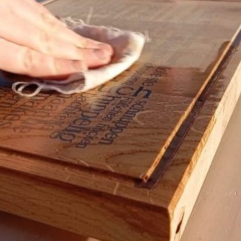 Hand mit Lappen, der Schneidebrett ölt